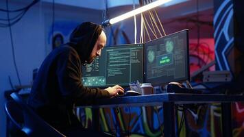 Hacker in graffiti painted warehouse celebrating after successfully tricking internet users into revealing sensitive information. Cheerful cybercriminal excited after stealing passwords video