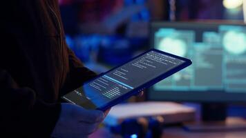 Hacker using VPN as anonymity tool to mask his online identity while committing data breaches using tablet. Cybercriminal in bunker masking his location, hacking with device, camera B close up video