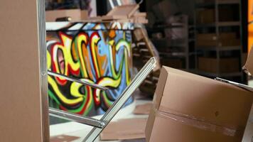 Wreckage left over by vandals in criminals headquarters with graffiti drawings sprayed on walls. Object thrown on floor in ghetto hideout after criminals rushed to evacuate place, handheld camera shot video
