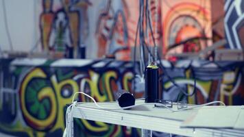 Close up of spray cans used by guerilla artists in building with graffiti drawings sprayed on walls. Paint cans in desolate industrial location used by teens to do art, concept of urban culture video