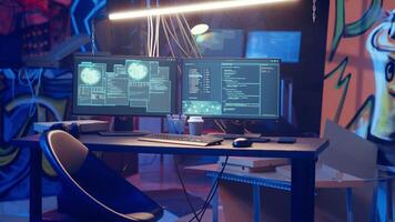 High tech computer system running malicious code in empty basement, handheld camera shot. PC monitors in empty neon lit criminal hideout used by hackers to commit illegal activities, camera B video