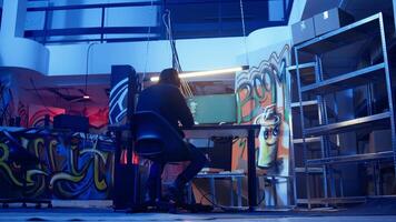 Hooded hacker leaving neon lit underground shelter after launching DDoS attack on websites. Cybercriminal finishing work on script that can crash businesses servers, exiting headquarters, camera A video
