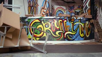 Empty vandalized property with graffiti paintings on walls, concept of alternative lifestyle. City slums ghetto location used as crime base of operations by hooligans doing street art, panning shot video