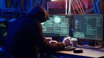 Hacker in abandoned warehouse talking on phone with partner, stealing data after using phishing technique. Man in telephone call with colleague, tricking users into revealing information, camera B video