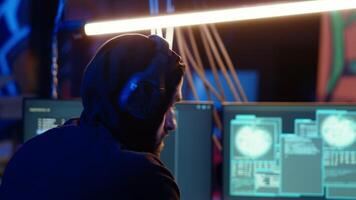 Hacker hiding in bunker removing headphones to hear suspicious sounds, feeling anxious after stealing data from victims. Man stopping music, scared about being caught by police, camera B close up video