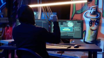 Hacker in hidden shelter excited after managing to launch successful DDoS attack on website, celebrating, crashing it by sending large amounts of traffic from multiple sources, camera B close up video