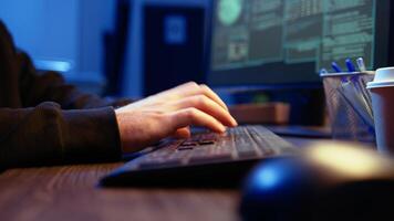Hacker in secret underground shelter typing on keyboard, writing lines of code on computer, trying to get past security systems with virus. Scammer working on hacking script, camera A close up shot video