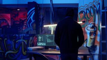 Hacker coming in secret base to use bugs and exploits to break into computer systems and access valuable data, bypassing firewalls, panning shot. Cybercriminal arriving in underground bunker video