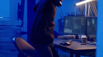 Hooded hacker creating pirating crack for software and game releases in bunker. Rogue programmer getting past anti tamper measures implemented by companies to protect their products, camera B video