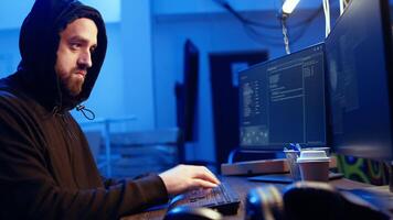 Close up of hacker in graffiti hideout focused on developing spyware software, using it to gather information from users computers without their knowledge, typing on keyboard, writing code, camera A video