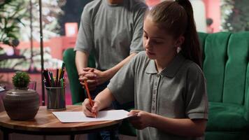 Teenage girl engages in a drawing activity as part of creative therapy session. Counseling with her mother and therapist focuses on using artwork for stress relief and emotional management. Camera A. video