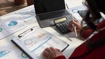 Senior woman accountant calculations and analyzing financial graph data with calculator and laptop Business video