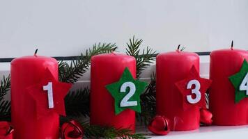 Countdown Four Advent red candles with numbers burning, fir branches and Christmas zero waste decorations in windowsill. Holiday preparation. Catholic traditions of Christmas new year winter holidays video
