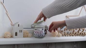 Woman taking candy from Original Advent Calendar made of glass jar and sweet chocolate candies Christmas concept. Countdown till winter holidays. Handmade advent calendar. Step by step DIY crafts do it yourself video