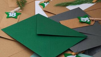 Number on craft envelopes notes with tasks before Christmas holidays. Female making kraft paper for handmade advent calendar Made with your own hands step by step DIY crafts do it yourself video