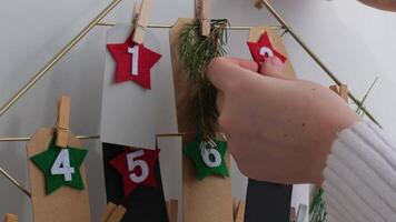 Number on craft paper notes with tasks before Christmas holidays. Female making kraft paper for handmade advent calendar Made with your own hands step by step DIY crafts do it yourself video