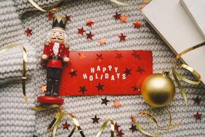 Festive holiday greeting with a nutcracker and decorations on a cozy knitted blanket photo