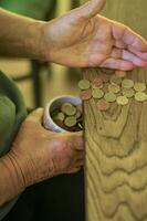 adult senior hands Sorting Small Change into a Container on a Wooden Table. High quality photo