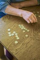 senior female sitting miserably at the table at home and counting coins. High quality photo