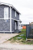The house is made of timber lined with gray brick. A house with a veranda. The concept of living outside the city. photo
