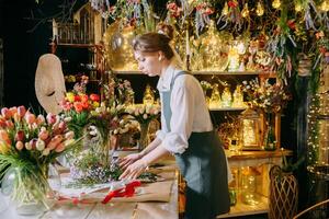 A woman in her florist shop collects bouquets of flowers. The concept of a small business. Bouquets of tulips for the holiday on March 8. photo