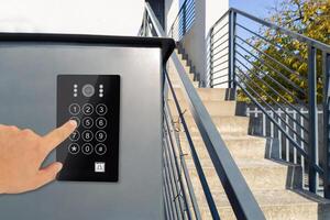 Hand using keypad on modern security system by stairs photo