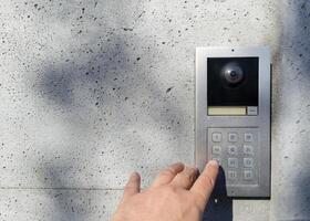Hand pressing keypad on modern intercom device photo