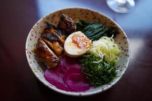 Japanese famous delicious ramen with different ingredients Noodle soup with shiitake, egg and pak choi cabbage on dark background. photo