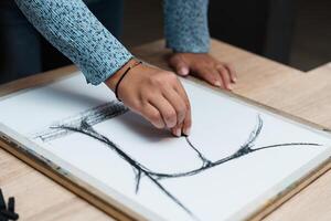 Person sketching abstract lines on paper with charcoal in a creative studio photo