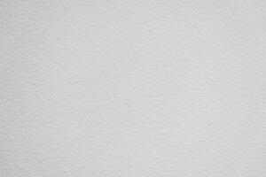 Plain white wall texture with subtle variations in shade, ideal for backgrounds in various design projects photo