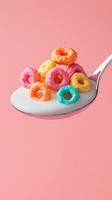 Colorful cereal loops on spoon with milk over pastel background photo