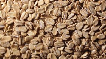 Oat Flakes Background Slowly Rotating Counter-Clockwise - Top View, Low Key Light. Scattered Dry Oat Flakes. Healthy Breakfast and Diet Eating Ingredients - Angular Rotation Left video