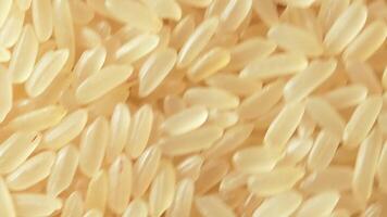 Dry Uncooked Parboiled Rice Background Rotating Clockwise - Top View, Close-Up. Scattered Raw Long Grain Rice. Asian Cuisine and Culture. Healthy Eating Ingredients. Diet Food. Angular Rotation Right video