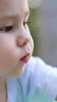 Portrait of an adorable Caucasian baby boy being busy with a toy. Close up. Side view. Blurred backdrop . Vertical video