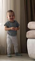 Adorable happy active toddler running by the room. Fun time at home. Vertical video