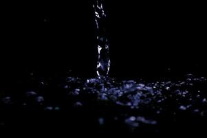 Water stream the air in dark. Splashing water fly in the air. Part of the drops is in focus, part - out of the focus. photo