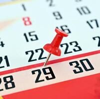 pushpin on a calendar date, reminder and time concept photo