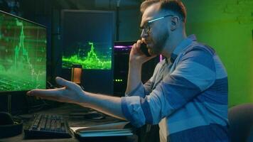 Angry Caucasian man male freelancer business crypto analyst talking mobile phone negotiations guy looking computer screen annoyed trader argue quarrel stress neon at home scam problem error night work video