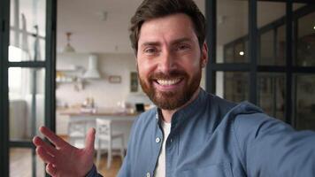 Glad Caucasian man male father smiling recording blog speaking camera mobile phone tech at home demonstrating new house happy guy dad discuss vlog household waving hand communication streaming video