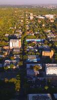 Vast urban panorama with lots of greenery on sunny daytime. Dense architecture of the city from aerial perspective. Vertical video