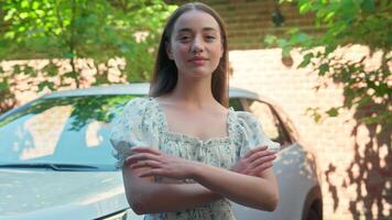 Confident successful happy Caucasian smiling woman girl female owner client looking at camera crossing hands crossed arms posing with new car buying automobile rental service test drive at city street video