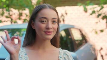 Glad happy smiling Caucasian woman female girl laughing client buyer customer car owner looking at camera showing okay good gesture recommend rental automobile buy transport test drive at city street video