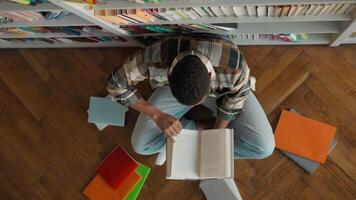 Top view unrecognizable African American man student reading book reader exam study learning library high school university turning pages male textbook pupil task guy bookstore college learner teenage video