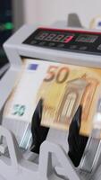 argent compte machine avec une liasse de cinquante euro billets de banque. proche en haut. portable ouvert à toile de fond dans se brouiller. verticale video