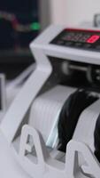 Small compact cash counting machine calculating American dollars. Equipment for financial operations. Close up. Vertical video