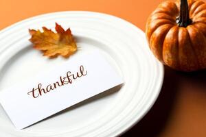 Modern minimalist Thanksgiving table setting featuring pumpkin and autumn leaves for an elegant celebration photo