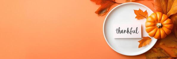 Modern minimalist Thanksgiving table setting featuring a pumpkin and autumn leaves on an orange background photo
