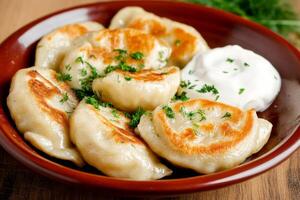 Delicious plate of traditional pierogi topped with caramelized onions and fresh dill on a rustic wooden table photo