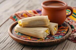 Traditional tamales served on a rustic wooden platter with hot chocolate and a colorful Mexican tablecloth photo