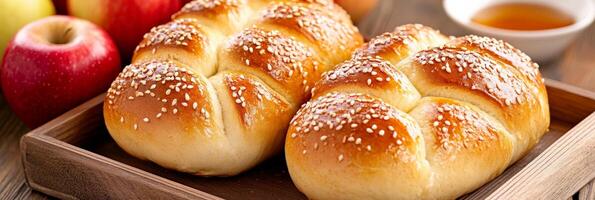 Two freshly baked challah breads with sesame and plain, served with apples and honey for a festive celebration photo